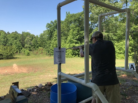 Man holds rifle at his station for the sporting clay tournament