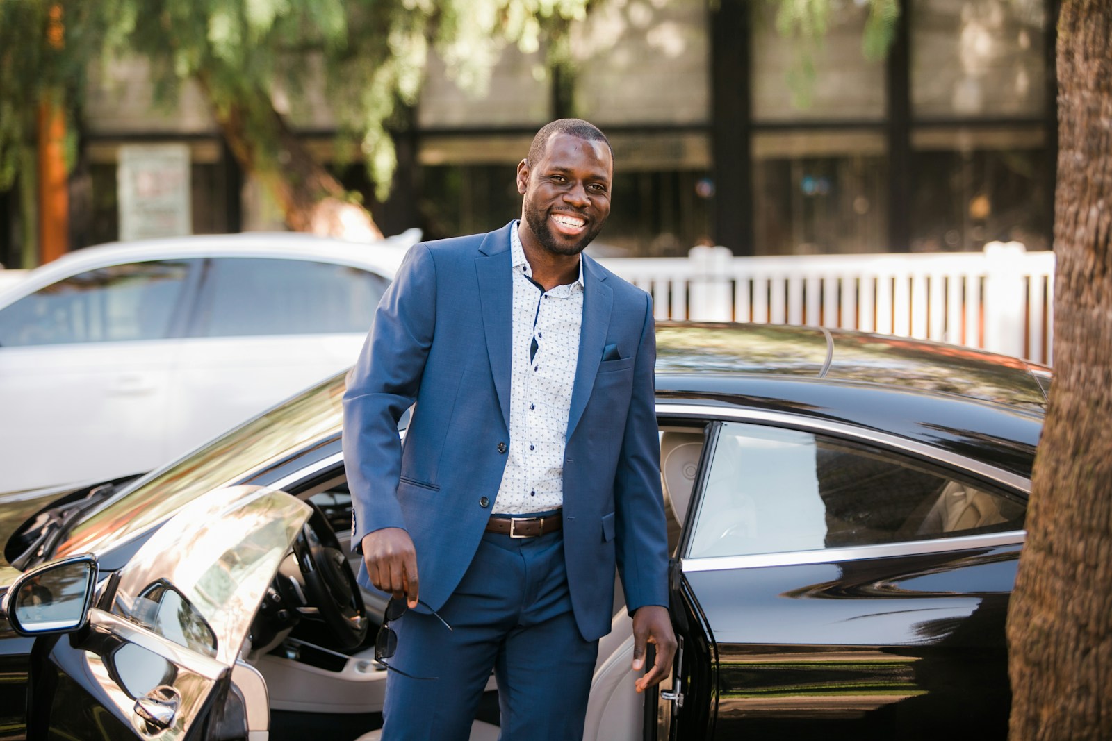 man in blue suit standing beside black car with auto insurance deductible