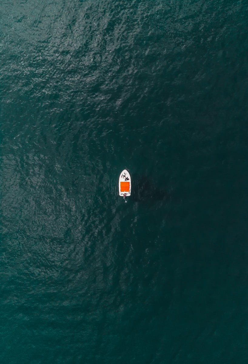 white and orange sailboat in the middle of ocean